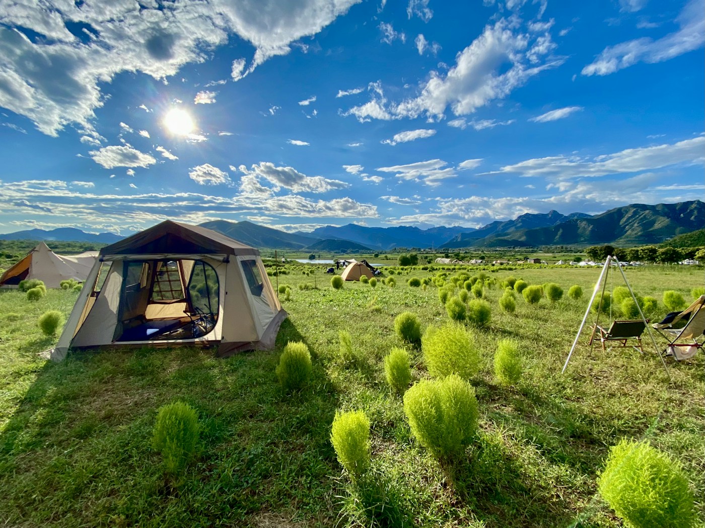 A tent in an open field with mountains behind it